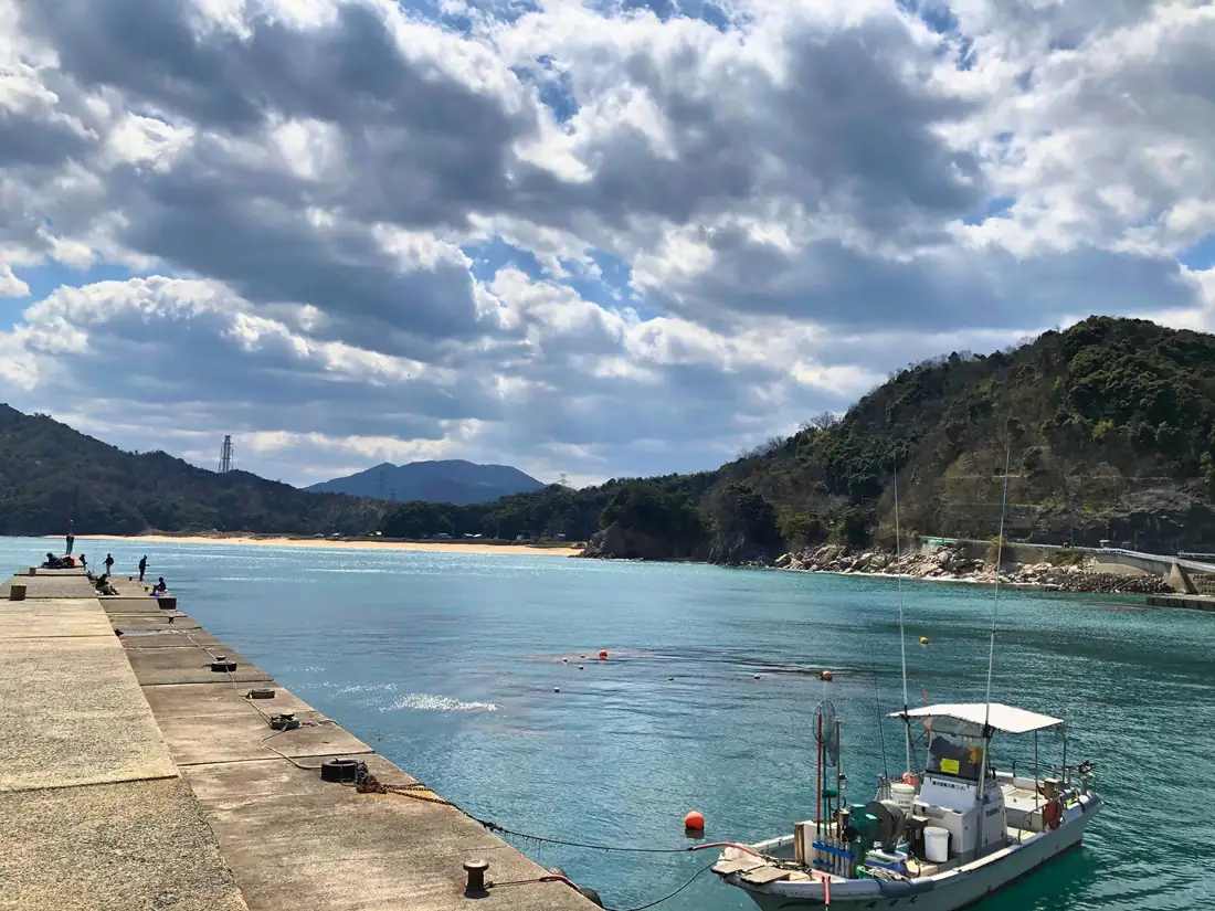 漁船が停まる開けた堤防と、山に囲まれた港